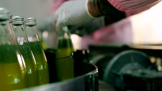 Worker sorting beverage bottles in production line.