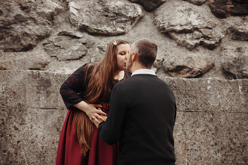 Beautiful and pregnant young woman kissing her husband while he touches her belly