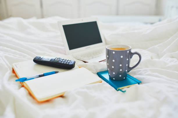 istock Laptop, notebook and phone in bed on clean white linens 1429919317