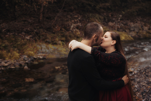 Cute couple hugging and kissing by the river in Autumn