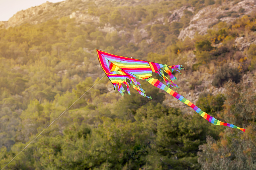 Beautiful, bright, striped, airy kite flies in the sky over the mountains