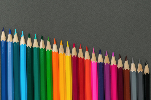 Multicolored wooden pencils on a gray background. Minimal concept of creativity. Flat lay.