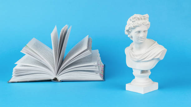 istock A plaster statuette and a large open book on a blue background. Minimal concept. 1429922905