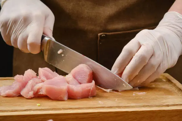 Cooking food. Sliced raw chicken meat on a wooden board. Shallow depth of field