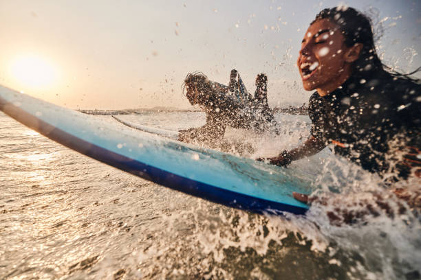 Carefree surfers having fun while surfing in sea at sunset. Copy space.