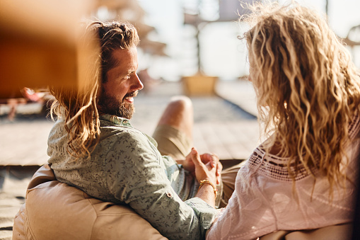 Happy man communicating with his girlfriend while relaxing in summer day on the beach.