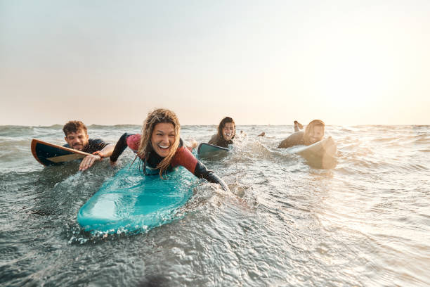 Cheerful surfers having fun in summer day at sea. Group of cheerful surfers having fun while surfing in summer day at sea. Copy space. wetsuit stock pictures, royalty-free photos & images