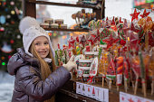 girl looks, chooses, buys caramel, lollipops, candies at the Christmas market