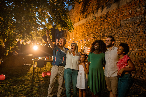 A multi-generation family watching an American holiday firework show from their back yard