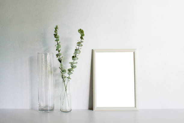 istock A white photo frame and green leaves on white table. 1429932334