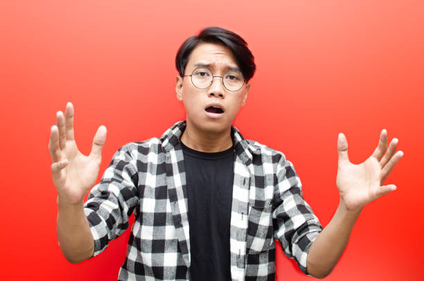 young asian man looks clueless, puzzled, confused, stressed and wondered with hand gesture asking why. isolated over red background. billboard advertisment model concept. - blank expression head and shoulders horizontal studio shot imagens e fotografias de stock