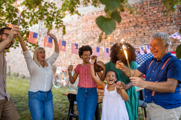 Multi-generation family waving sparklers outdoors on an American national holiday A multi-generation family waving sparklers outdoors on an American national holiday fourth of july photos stock pictures, royalty-free photos & images