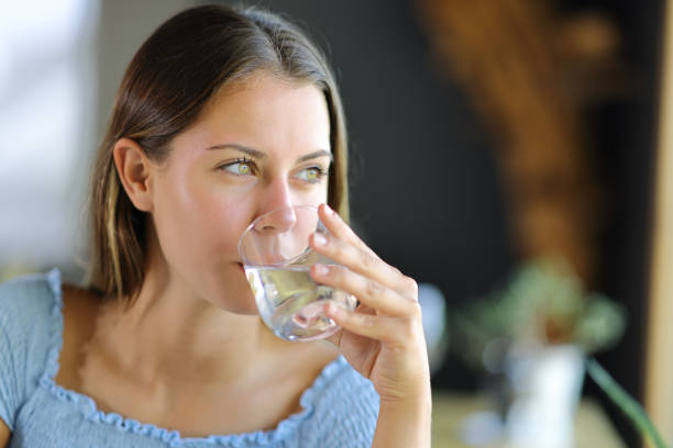 Woman drinking water from glass contemplating stock photo