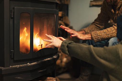 Father and son warming hands by a fireplace