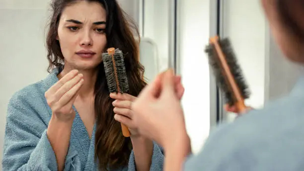 Woman losing hair on hairbrush in hand