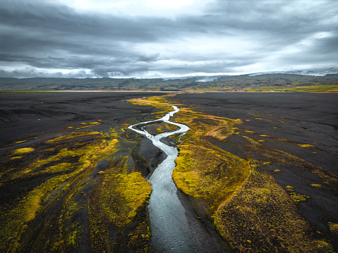 Amazing yellow and golden river flowing through Solheimasandur nearby the plane wreckage. Beautiful Iceland from above, aerial view.