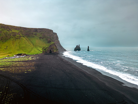 Reynisfjara is a world-famous black sand beach on the South Coast of Iceland. Basalt rocks Reynisdrangar, black volcanic sand and Atlantic ocean in Iceland