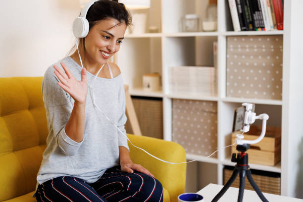istock Beautiful female content maker using mobile phone for online broadcasting at home 1429953171