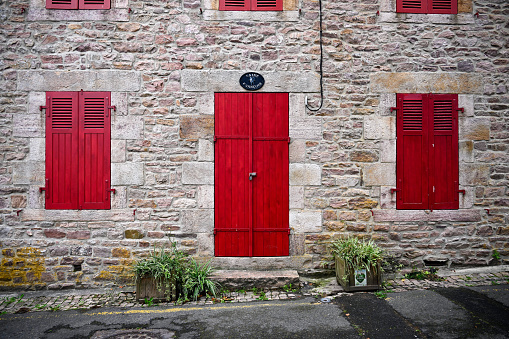 Erquy, France, September 15, 2022 - Breton stone house with red door in Erquy, France