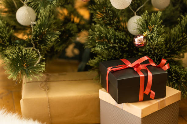 istock Beautiful Christmas gift boxes on floor near fir tree in room. 1429953636