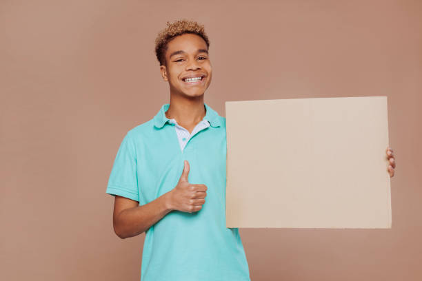 istock Young cheerful boy holds advertising banner at studio 1429956842
