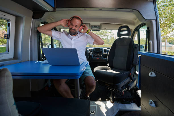istock Happy middle-aged man putting on his headset to start working on his laptop from his camper van. 1429962339