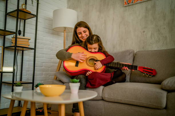 istock Mother and daughter playing guitar at home 1429965298