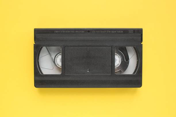 istock Black VHS videotape recorder cassette on yellow background. Old obsolete technology for tape recording and watching media movies. 1429967309