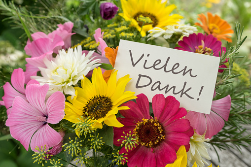 Colorful bouquet of summer flowers with card and German text: Many Thanks