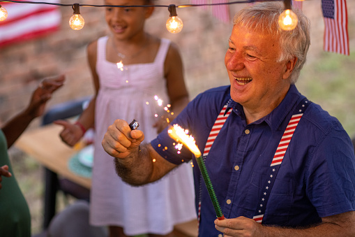 Multi-generationfamily having fun with sparklers while celebrating American holiday