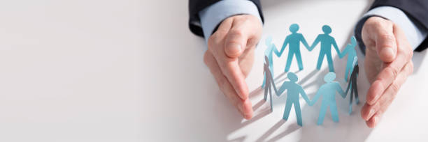 istock Businessperson's Hand Protecting Paper Cut Out Figures 1429968722