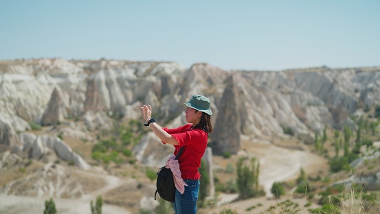 A young female tourist is using a smart phone and taking photos and videos of nature in Cappadocia Türkiye.