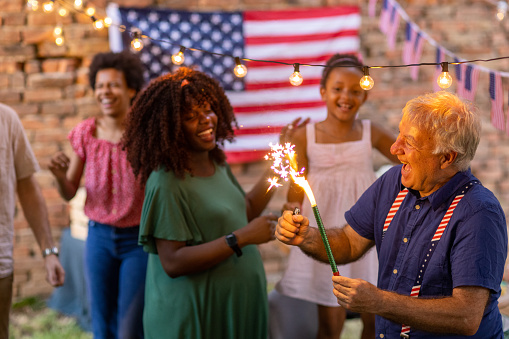 Multi-generationfamily having fun with sparklers while celebrating American holiday