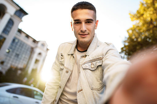 Portrait of young man taking a selfie while out on the city street, close up selfie