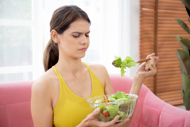 istock Young caucasian woman sitting on sofa eating vegetable salad while feeling dislike and expression disgusted, woman emotion frustrated with anorexia vegetarian and hate, nutrition food concept. 1429973199