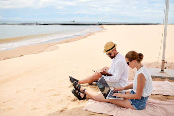 paar, das online am strand arbeitet - beach men isolated tourist stock-fotos und bilder