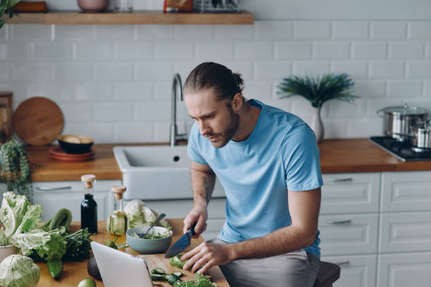 istock Handsome young man looking at digital tablet while preparing food at the domestic kitchen 1429975624
