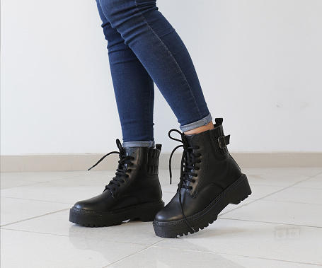 woman  in black leather shoes or boots from the new collection , girl's legs in fashionable eco-leather shoes fall-winter indoor
