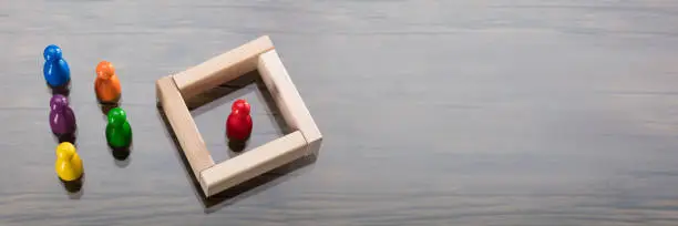 Red Figurine Pawn Separated By Wooden Blocks From Colorful Figurines