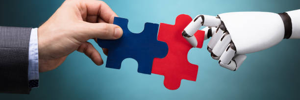 istock Businessperson And Robot Holding Jigsaw Puzzle 1429981305