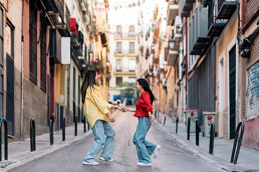 Young and pretty asian female friends walking and having fun in the streets of Madrid.
