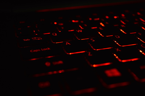 A closeup of a keyboard with a red backlight on isolated background