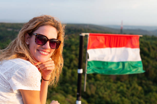 jeune femme caucasienne joyeuse en lunettes de soleil se relaxant dans la nature au drapeau hongrois - drapeau hongrois photos et images de collection