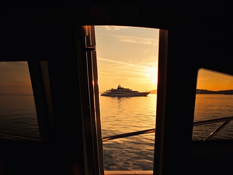 Yacht at sea in Greek Islands. Perspective through another yacht’s windows, at sunset.