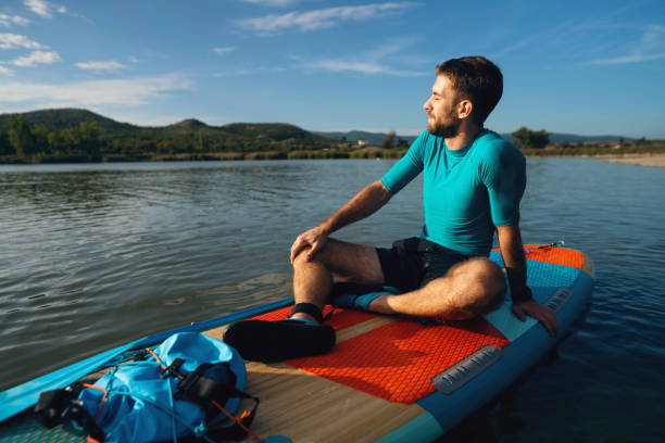 istock Caucasian man sitting on a standup paddleboard, while enjoying the sunset view 1429986641