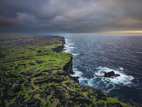 Aerial view of icelandic cliff coast with rough ocean water and waves.