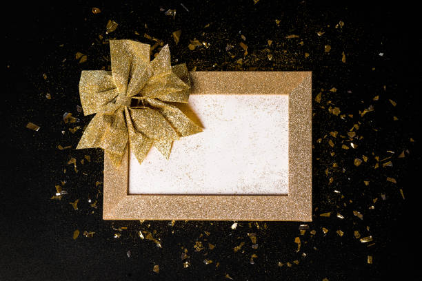 istock Gold frame from glitters with a gold bow on a black background. Greeting cards.Copy space. New Year's card background.Close-up.Simple minimalistic . 1429989104