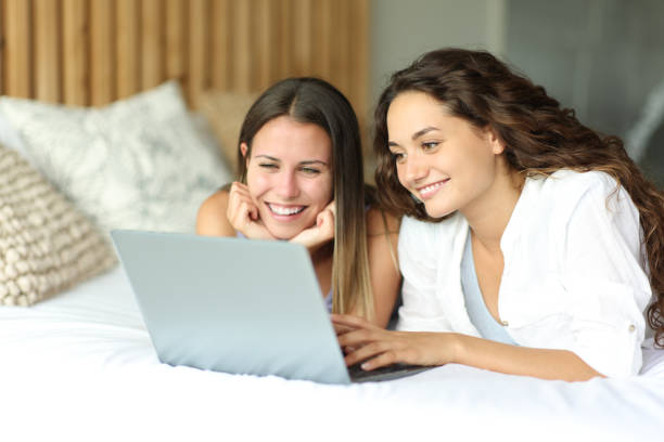 istock Happy women watching media on laptop on a bed 1429989441