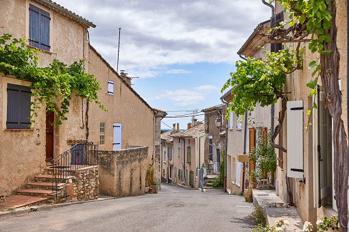 The narrow streets of the small village in provence, Valensole. On a sunny day in France, the facades of the old houses are overgrown with all kinds of plants.