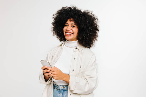 istock Happy young woman smiling at the camera while holding a smartphone 1429991255